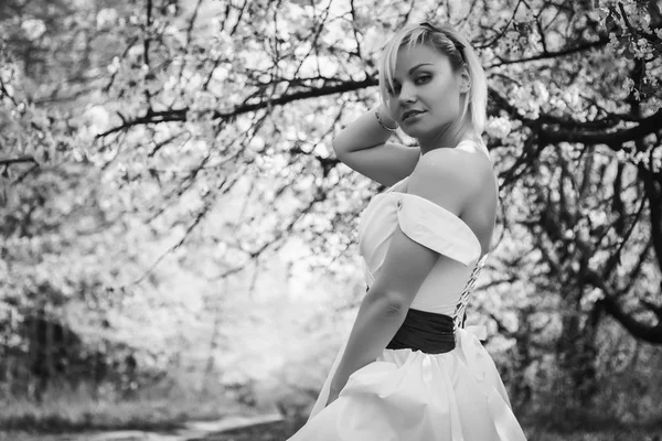 Rubia en vestido blanco en jardín de primavera — Foto de Stock