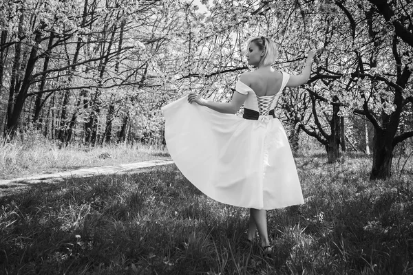 Blondýnka v bílých šatech v jarní zahradě — Stock fotografie