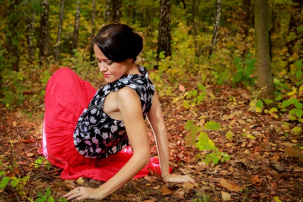 Kvinna i röd klänning i höstens park — Stockfoto