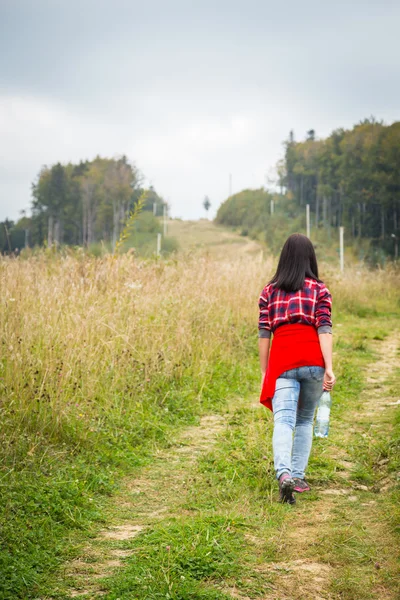 Girl in casual clothes climbs uphill — Stock Photo, Image