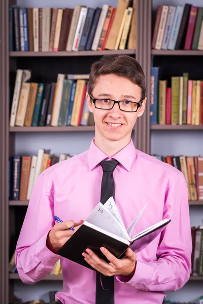 Студент держит книгу в библиотеке — стоковое фото