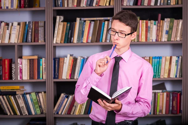 Student hält Buch in der Bibliothek — Stockfoto