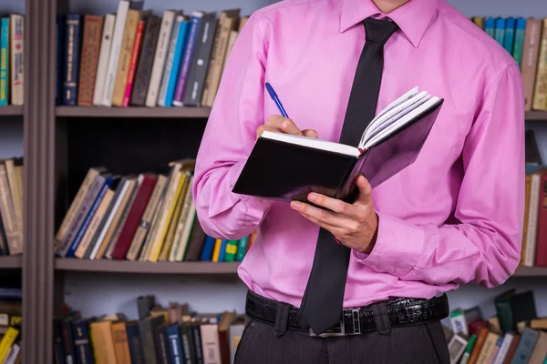 Student hält Buch in der Bibliothek — Stockfoto