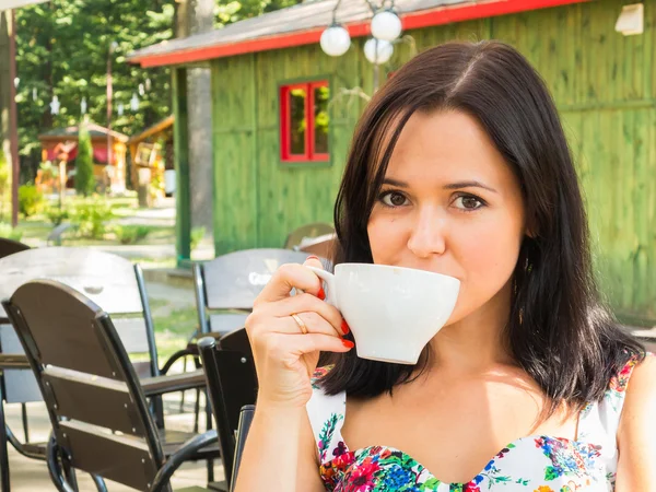 Mladá žena pít kávu v café terrace — Stock fotografie