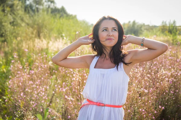 Meisje in witte jurk staande in hoog gras — Stockfoto