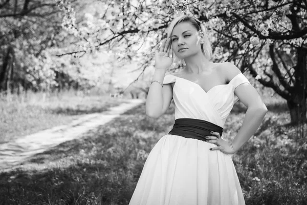 Rubia en vestido blanco en jardín de primavera — Foto de Stock