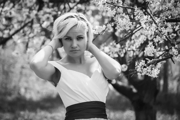 Blondine im weißen Kleid im Frühlingsgarten — Stockfoto