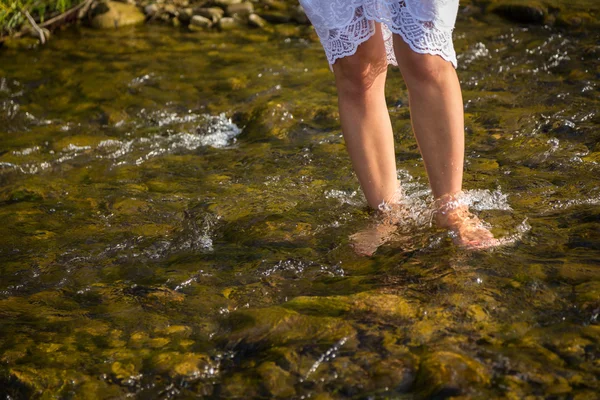 Jambes femelles sur un ruisseau sauvage — Photo