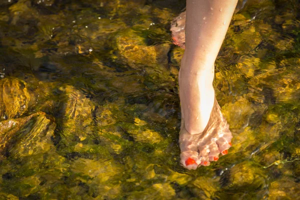 Female legs on a wild brook — Stock Photo, Image