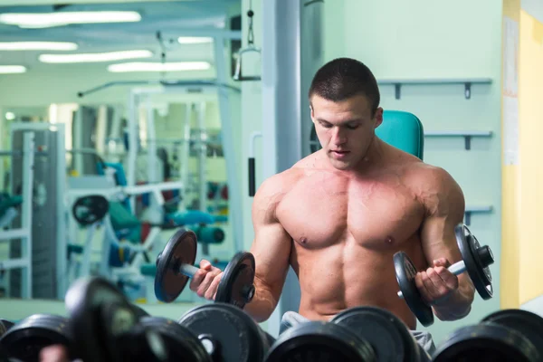 Homem musculoso trabalhando com halteres — Fotografia de Stock