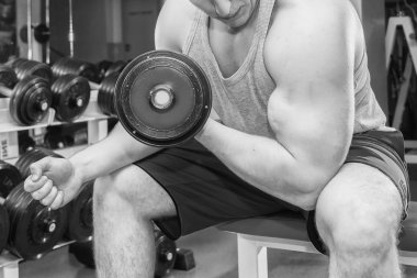 Adam bir dumbbell tutarak kaslı kollarıyla