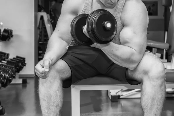 Man with muscular arms holding a dumbbell — Stock Photo, Image