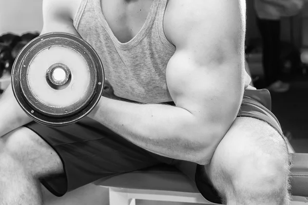 Homme aux bras musclés tenant un haltère — Photo