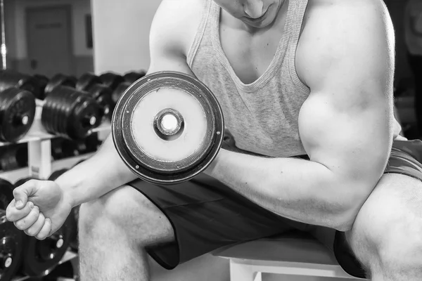 Homem com braços musculares segurando um halteres — Fotografia de Stock