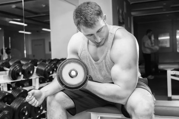 Man with muscular arms holding a dumbbell — Stock Photo, Image