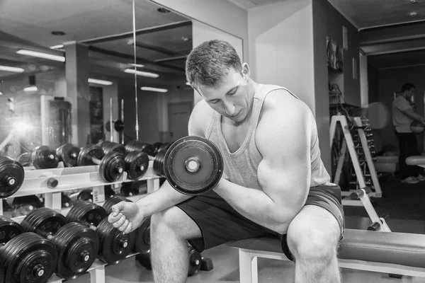 Homem com braços musculares segurando um halteres — Fotografia de Stock