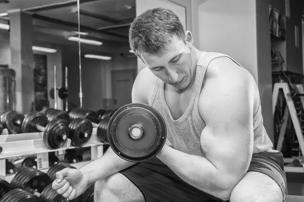 Man with muscular arms holding a dumbbell — Stock Photo, Image