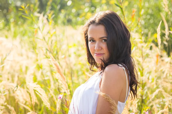 Fille en robe blanche debout dans l'herbe haute — Photo