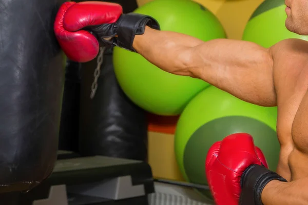 Muscular man hit a punching bag — Stock Photo, Image