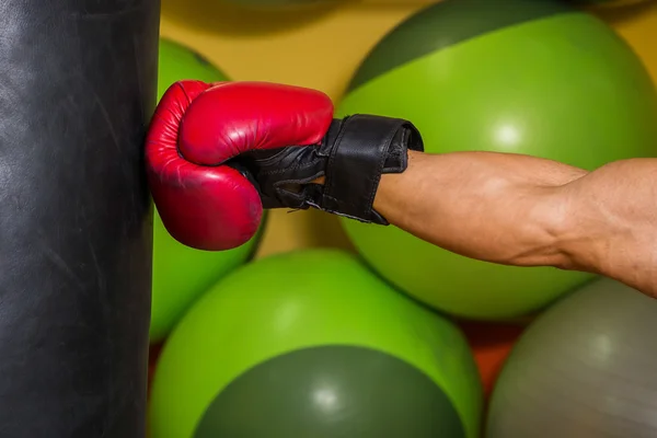 Muscular man hit a punching bag — Stock Photo, Image