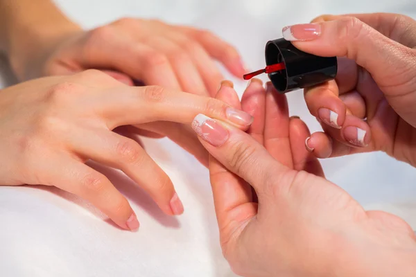 Woman applying nail varnish to nails