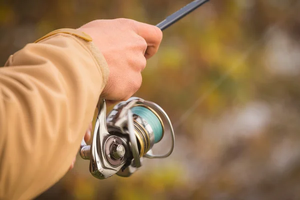 Fisherman with spinning on river bank — Stock Photo, Image