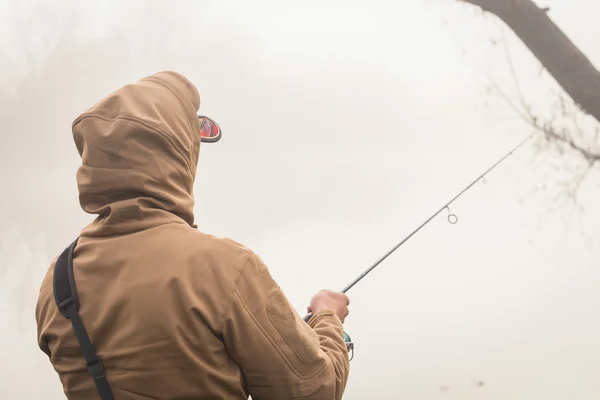 Pescador con hilado en la orilla del río — Foto de Stock