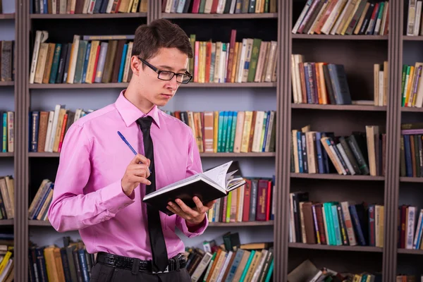 Student hält Buch in der Bibliothek — Stockfoto