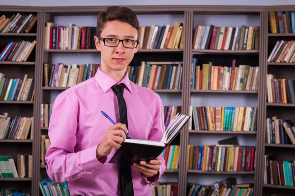 Student hält Buch in der Bibliothek — Stockfoto