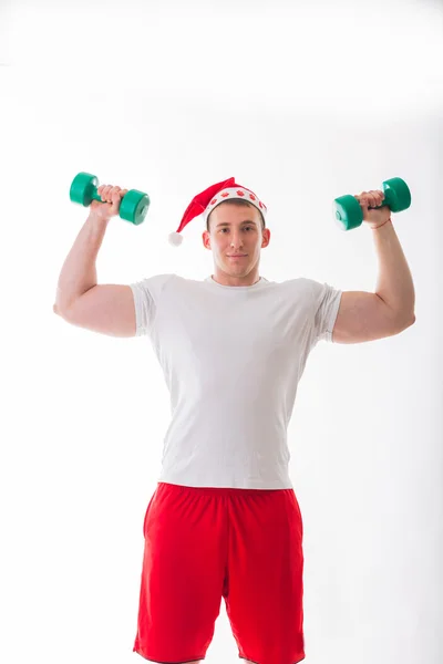 Man in a Christmas hat holding a dumbbells — Stock Photo, Image