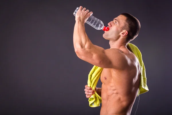 Uomo atletico che beve acqua dalla bottiglia — Foto Stock