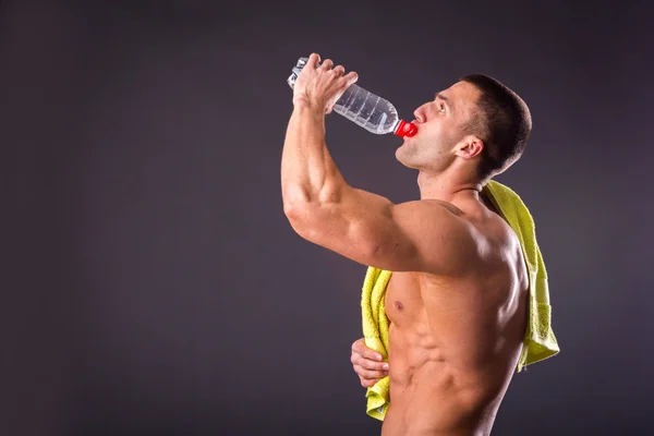 Uomo atletico che beve acqua dalla bottiglia — Foto Stock