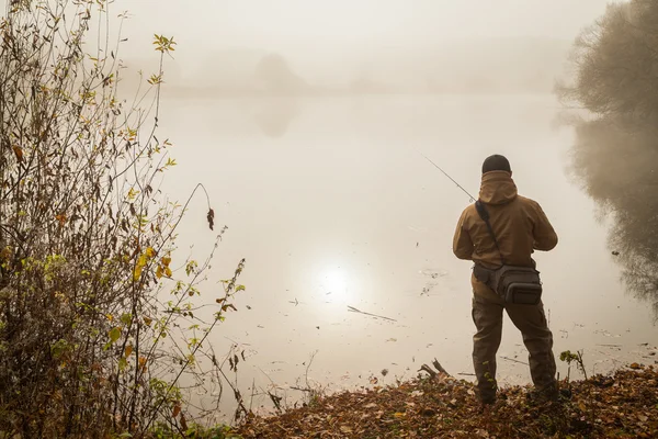 Pescador con hilado en la orilla del río — Foto de Stock