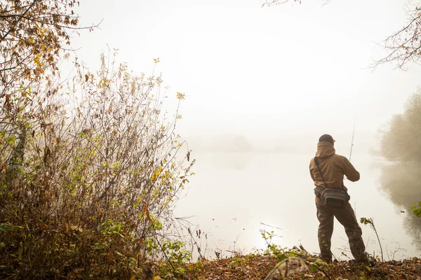 Fisherman with spinning on river bank — Stock Photo, Image