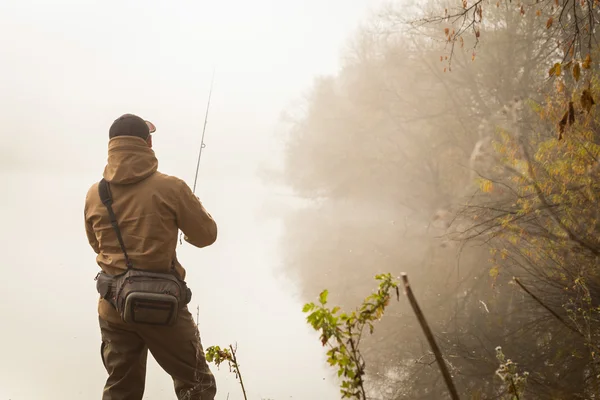 Рыбак со спиннингом на берегу реки — стоковое фото
