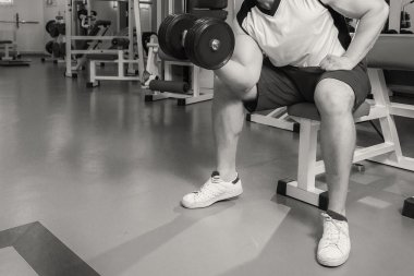 Adam bir dumbbell tutarak kaslı kollarıyla