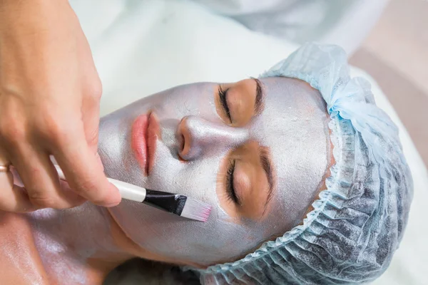 Terapeuta aplicando máscara no rosto da mulher — Fotografia de Stock