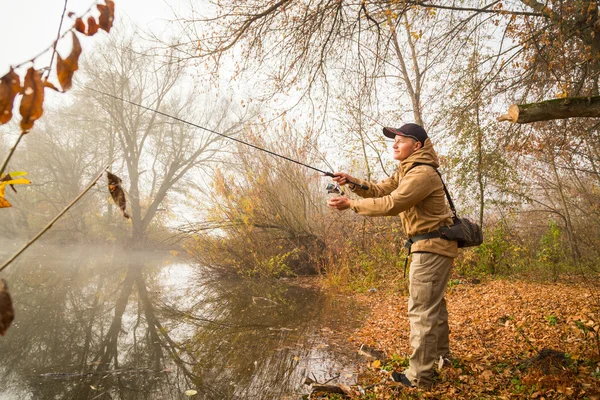Pescador con spinning en la orilla del río — Foto de Stock