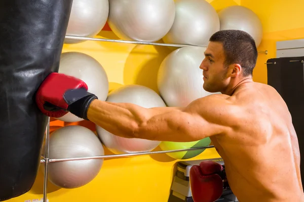 Uomo muscoloso in guanti da boxe in palestra — Foto Stock