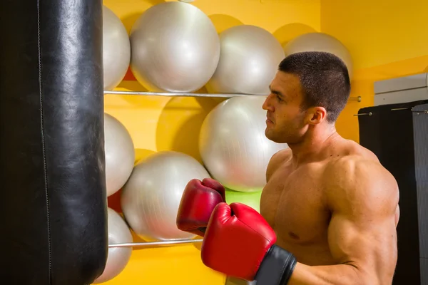 Uomo muscoloso in guanti da boxe in palestra — Foto Stock