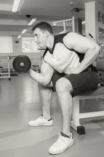 Homme aux bras musclés tenant un haltère — Photo