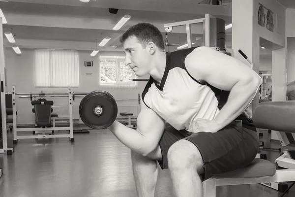 Man with muscular arms holding a dumbbell — Stock Photo, Image