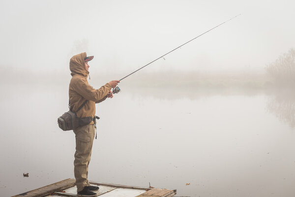 Fisherman with spinning on river bank