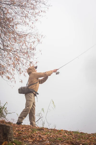 Fisherman with spinning on river bank — Stock Photo, Image