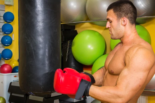 Uomo muscoloso in guanti da boxe in palestra — Foto Stock