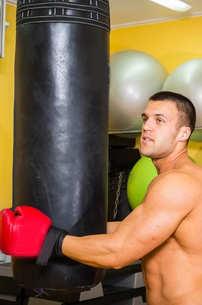 Uomo muscoloso in guanti da boxe in palestra — Foto Stock