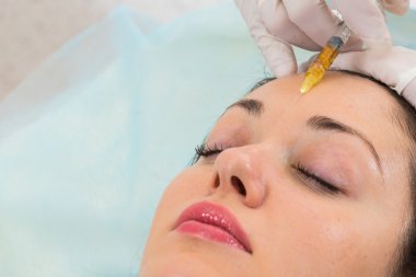 Güzellik uzmanı hastanın yüz içine enjeksiyon yapar