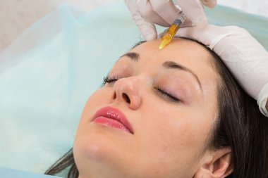 Güzellik uzmanı hastanın yüz içine enjeksiyon yapar
