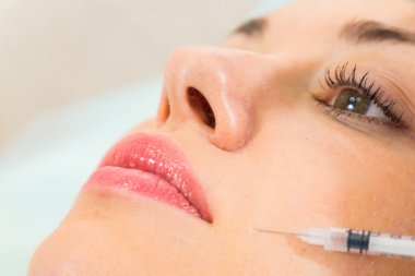 Güzellik uzmanı hastanın yüz içine enjeksiyon yapar