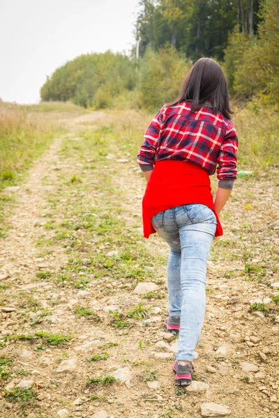 Girl in casual clothes climbs uphill — Stock Photo, Image